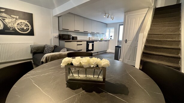 A modern kitchen with white cabinets, a microwave, and a window. - Oxford Bolthole | Oxford Holiday Let | 2 Beds & Sleeps 4 (Oxford)