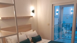 Ein Hotelzimmer mit Bett, kleinem Tisch und einem Balkon mit Meerblick.