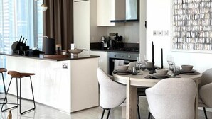Cocina moderna con una isla central, comedor con sillas y un amplio ventanal con cortinas.