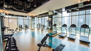 Un gimnasio moderno con cintas de correr, máquinas de pesas y un banco.