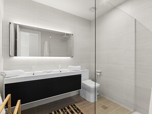 A modern bathroom with a large mirror, a black vanity, a toilet, and a shower area. - B-404 Stunning one bedroom corner apartment (Cupecoy)