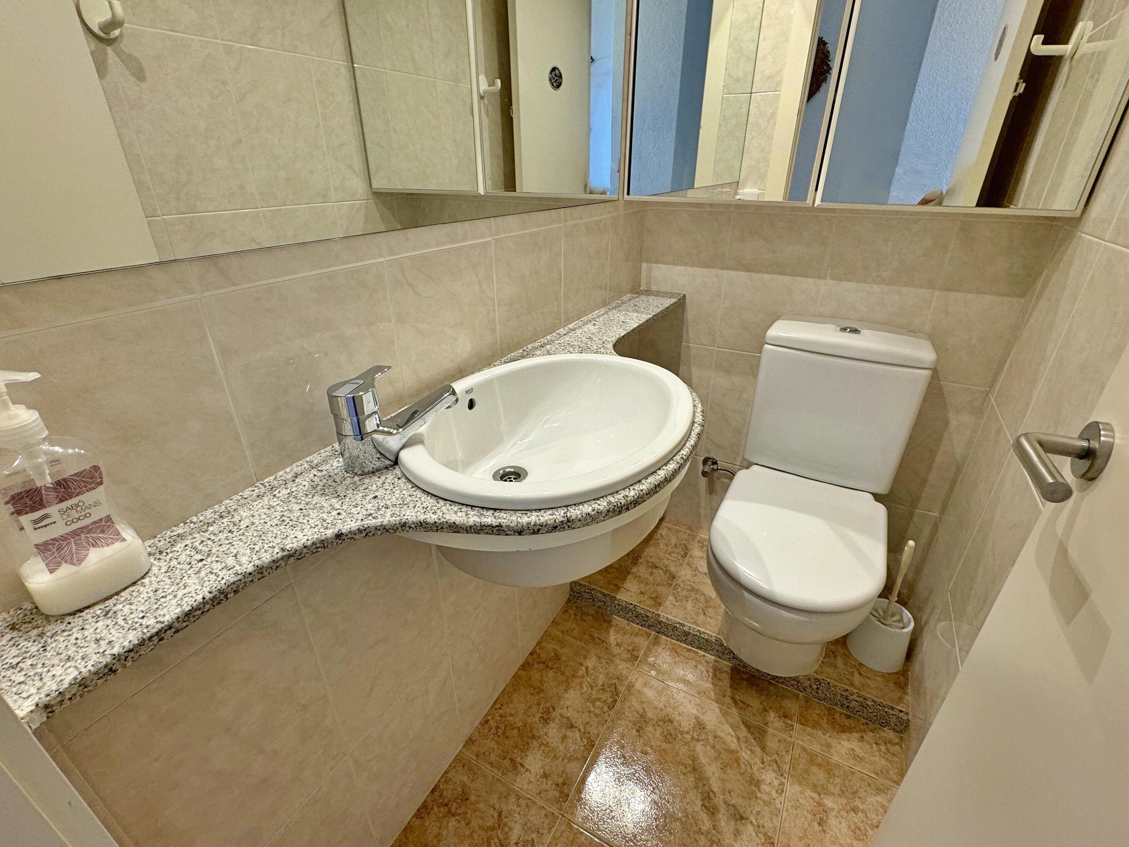 A bathroom with a white sink, a toilet, and a mirror.