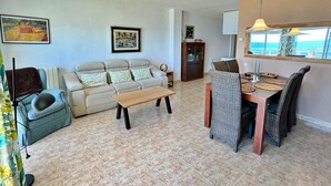 Ein Wohnzimmer mit Sofa, Couchtisch, Esstisch mit Stühlen und Kunstwerken an den Wänden.