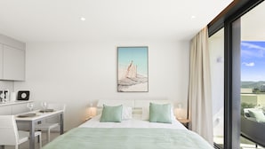 A modern hotel room with a large bed, a dining area, and a view of the city. - B-603 (Cupecoy)