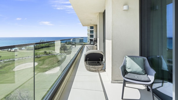 A balcony with a view of the ocean, a chair, and a small table. - B-603 (Cupecoy)