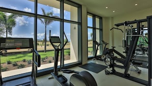 A gym with large windows, exercise equipment, and a view of a park. - B-603 (Cupecoy)