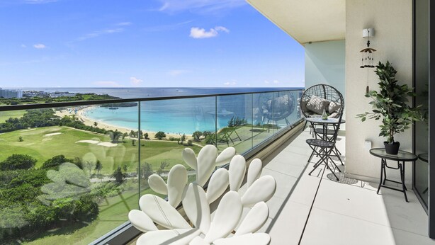 Ein Balkon mit Blick auf Strand und Meer, ein runder Tisch mit Stühlen und ein Blumentopf.