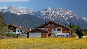 Ein Berggasthof mit traditioneller Architektur, ein Schild mit der Aufschrift 'Gästehaus Christofhol' und Blick auf schneebedeckte Gipfel.
