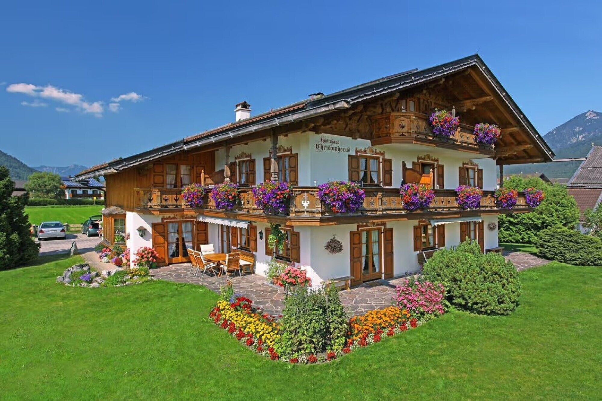 Eine zweistöckige Chalet mit Holzbalkonen, Blumenkästen und einem Steinfundament.
