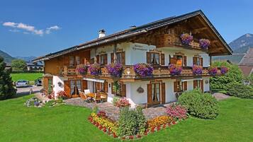 Eine zweistöckige Chalet mit Holzbalkonen, Blumenkästen und einem Steinfundament.