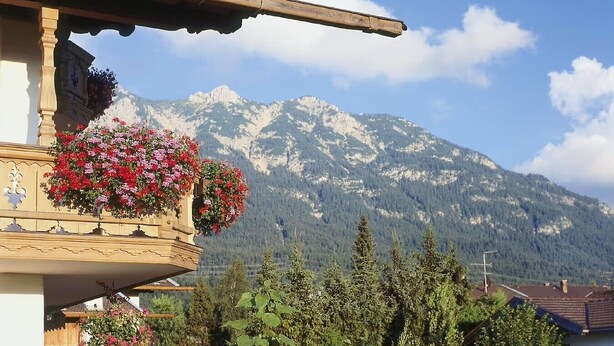 A mountain view with a balcony adorned with flowers.