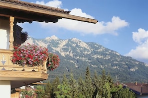 A mountain view with a balcony adorned with flowers. - Guesthouse Christophorus - Apartment "Alpenglühn" with Mountain View, Shared Garden & Wi-Fi (Krün)