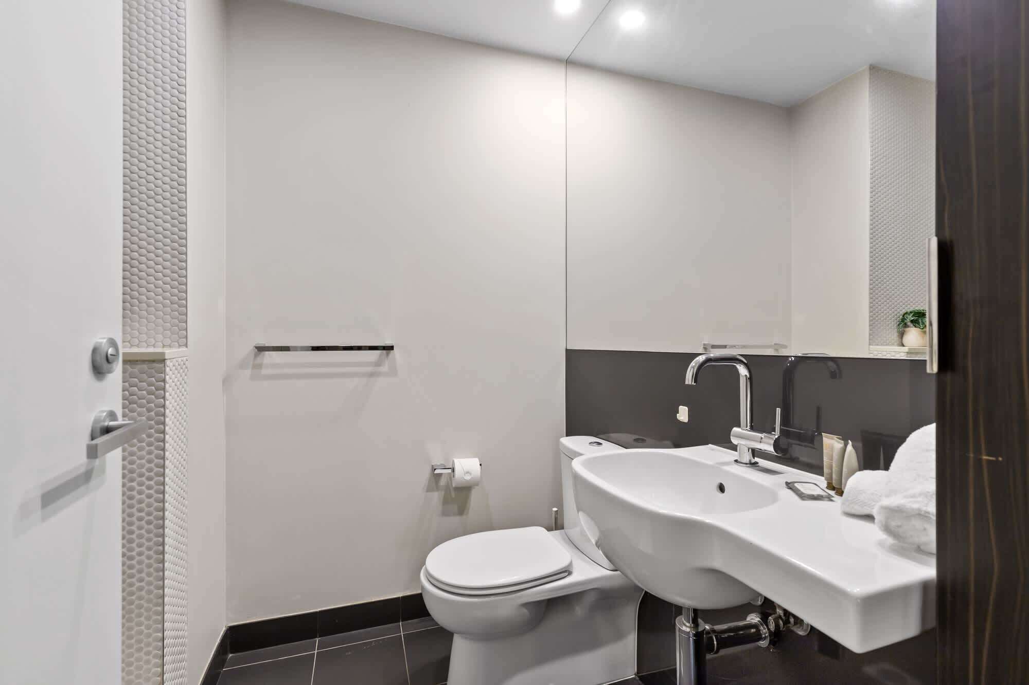 A modern bathroom with a toilet, sink, and mirror.