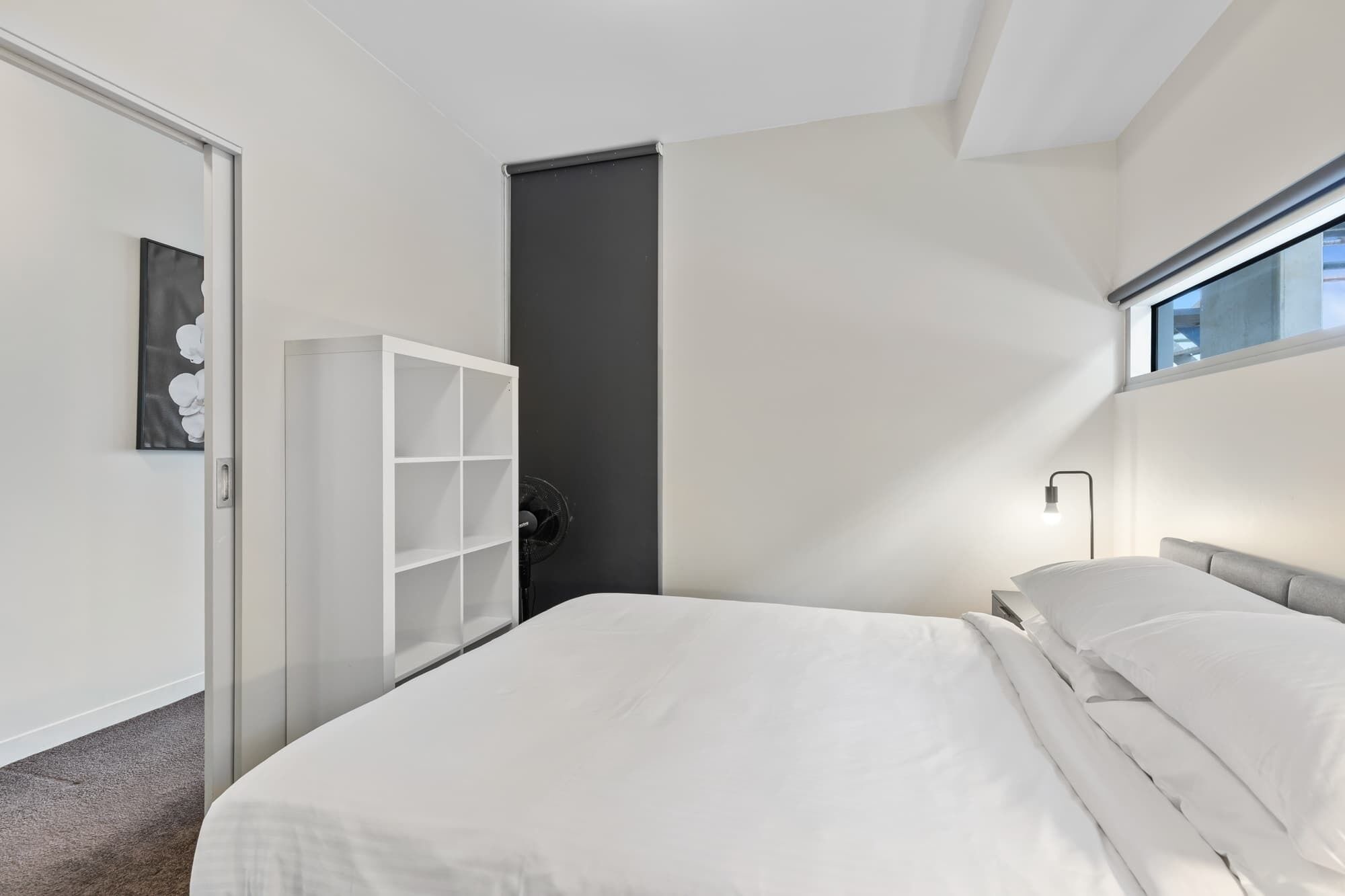 A modern bedroom with a bed, a wardrobe, a door, and a window.
