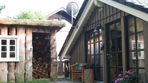 Un chalet rustique avec une façade en bois, une cheminée en pierre et une terrasse dotée de meubles d’extérieur.