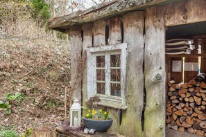 A rustic wooden cabin with a window, a birdhouse, a lantern, and a flower pot.