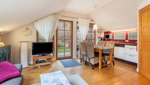 Un salon confortable avec un téléviseur, un coin repas et une cuisine.