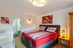Un dormitorio con cama, mesita de noche, lámpara y una obra de arte en la pared.