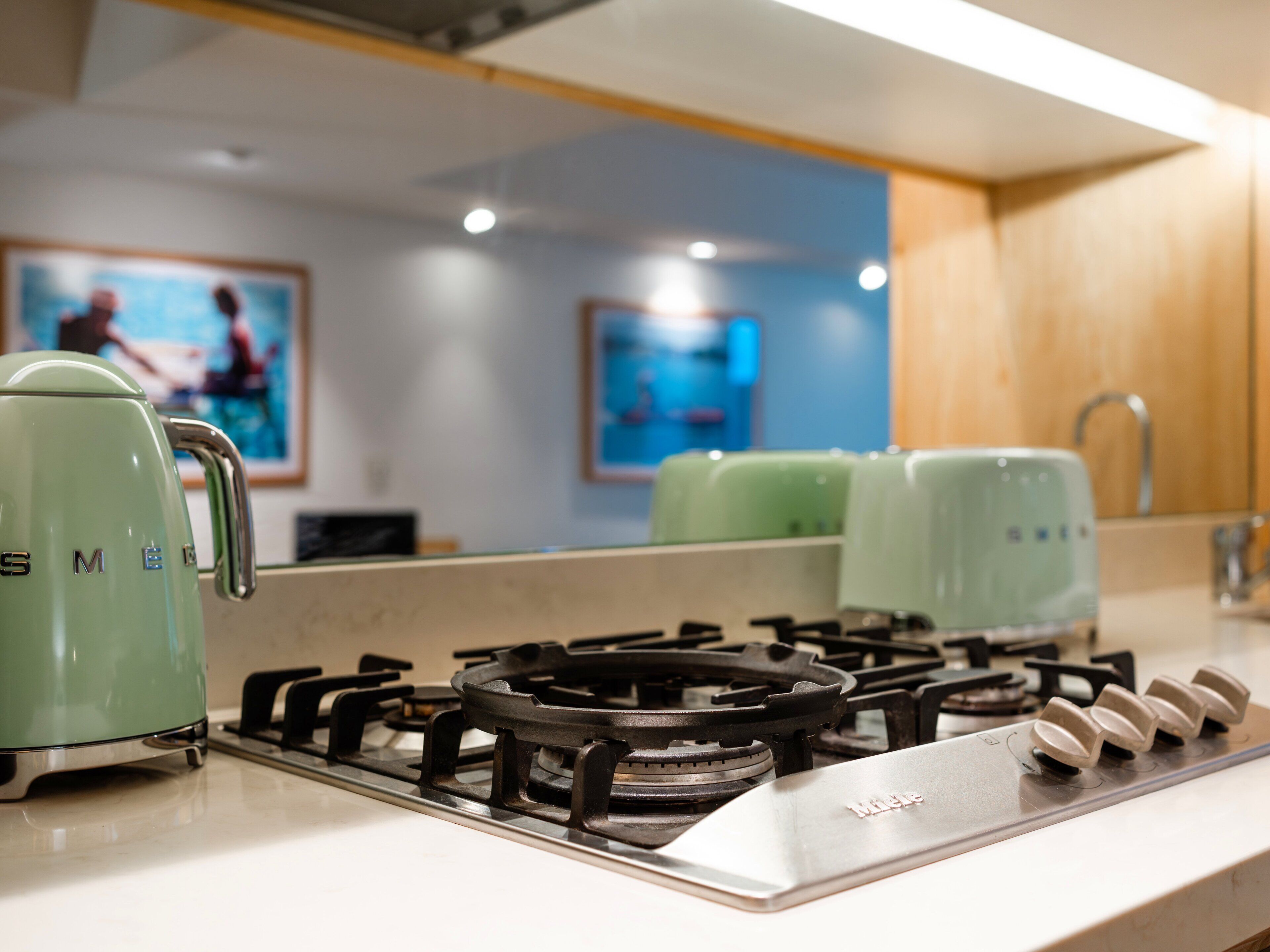 A kitchen with a gas stove, a green kettle, and a microwave.