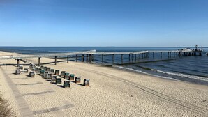 A beach with a pier, rows of beach chairs, and a boardwalk. - Apartment "Melosine" with Balcony (Koserow)