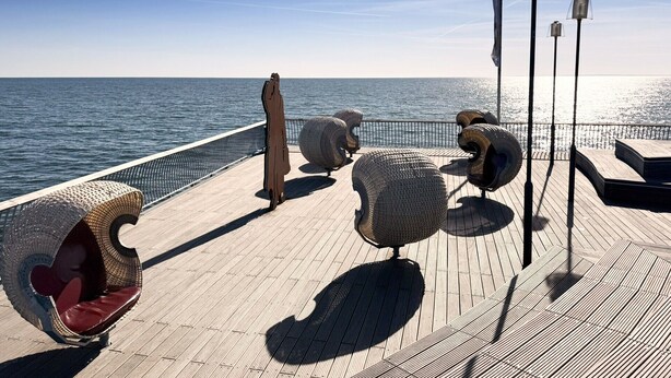 A wooden deck with seating areas and a railing overlooking a body of a water. - Apartment "Melosine" with Balcony (Koserow)