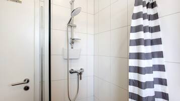 Une douche équipée d’un pommeau de douche à main, d’un robinet mural et d’un rideau de douche.