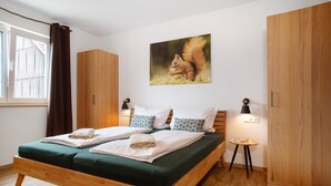 A double bed with green bedding, wooden wardrobe, and a wall-mounted squirrel picture.