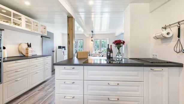 A modern kitchen with white cabinetry, a black countertop, and a central island. - Holiday Home "Luis - Hus" with 2 Private Terraces, Garden, and Wi-Fi (Dagebüll)