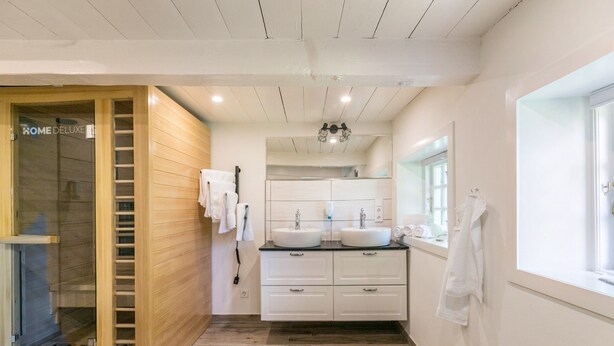 A modern bathroom with a wooden shower enclosure, a double sink vanity, and a large mirror.