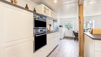 A kitchen with white cabinets, a double oven, and a countertop with kitchen utensils.