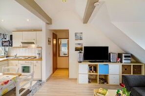 Un espace de vie compact comprenant un coin cuisine, un téléviseur à écran plat, un canapé et un coin repas.