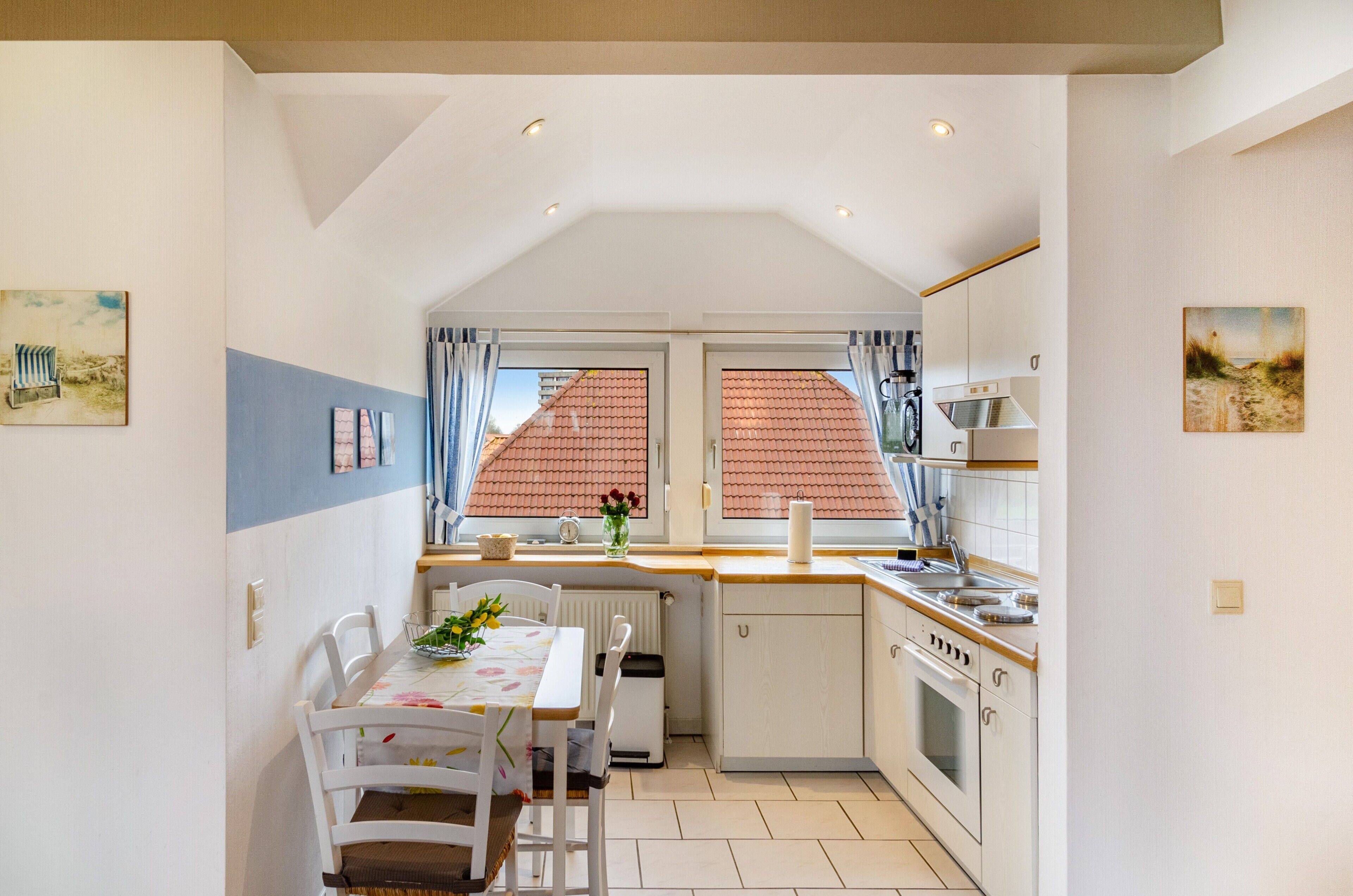 A compact kitchen with a dining area, a window with curtains, and a radiator under the table.