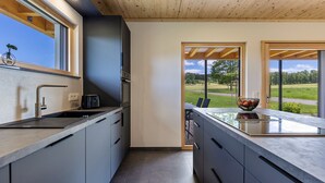 Een moderne keuken met een groot eiland, inbouwapparatuur en uitzicht op de omgeving.