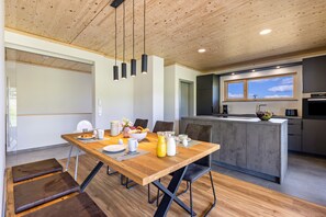 Une cuisine moderne avec un plafond en bois, un coin repas doté d’une table en bois et une grande fenêtre.