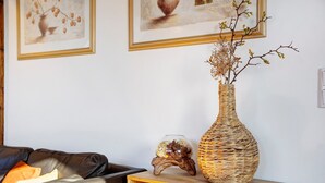 A living room with a sofa, a wooden side table with a vase and a decorative bowl, and framed artwork on the wall. - Apartment 'Gemütliche Ferienwohnung In Seenähe' with Shared Terrace, Shared Garden and Wi-Fi (Neustrelitz)