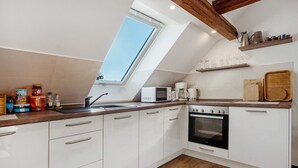 A modern kitchen with white cabinets, a wooden countertop, a skylight, and a built-in oven. - Apartment 'Gemütliche Ferienwohnung In Seenähe' with Shared Terrace, Shared Garden and Wi-Fi (Neustrelitz)