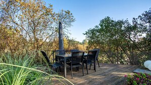 An outdoor wooden deck with a table and chairs, surrounded by greenery and trees. - Apartment 'Gemütliche Ferienwohnung In Seenähe' with Shared Terrace, Shared Garden and Wi-Fi (Neustrelitz)