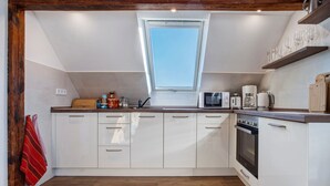 A kitchen with white cabinets, a microwave, a coffee maker, and a window above the sink. - Apartment 'Gemütliche Ferienwohnung In Seenähe' with Shared Terrace, Shared Garden and Wi-Fi (Neustrelitz)