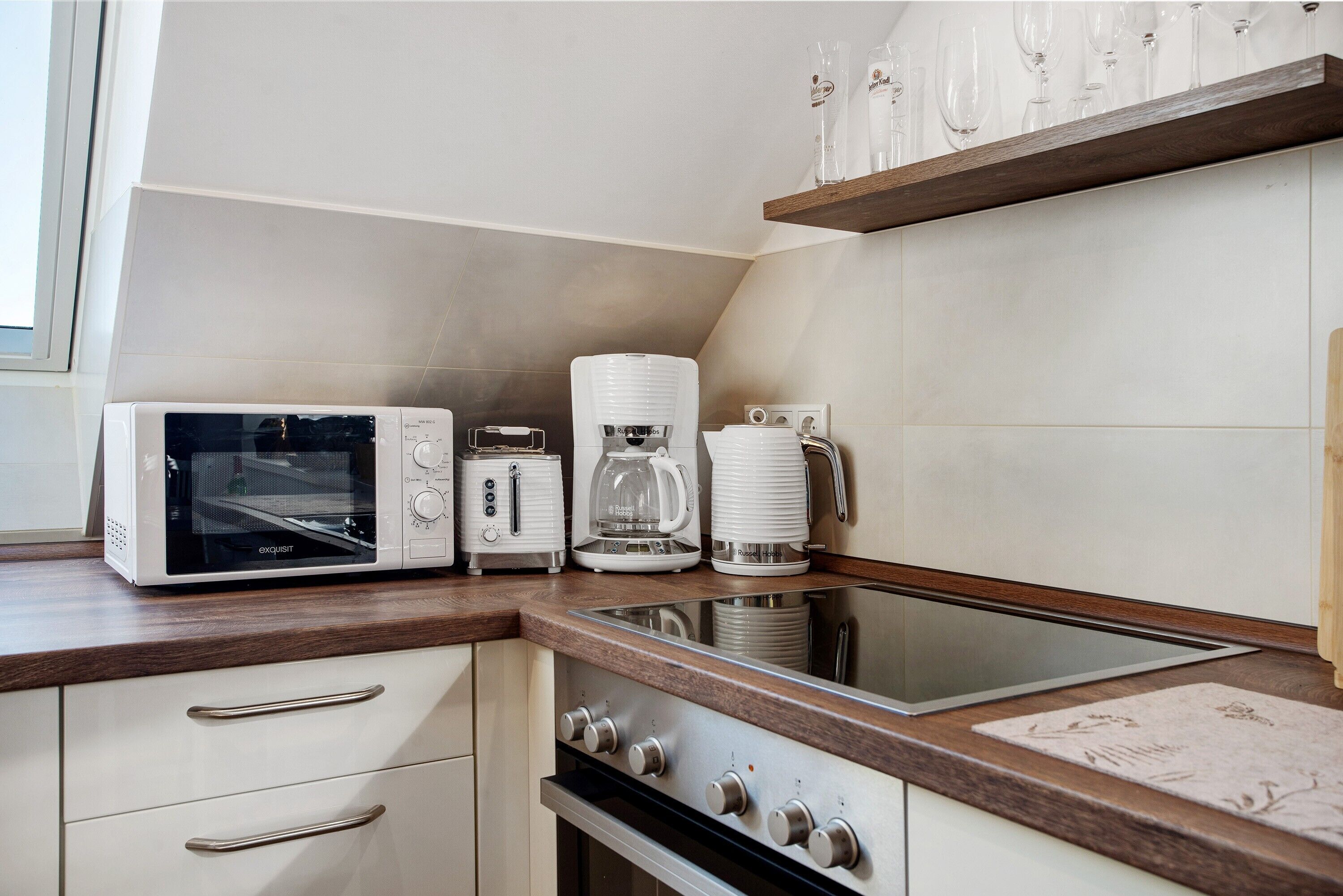 A kitchen with a microwave, toaster, coffee maker, and a stainless steel sink.