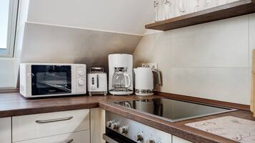 A kitchen with a microwave, toaster, coffee maker, and a stainless steel sink.