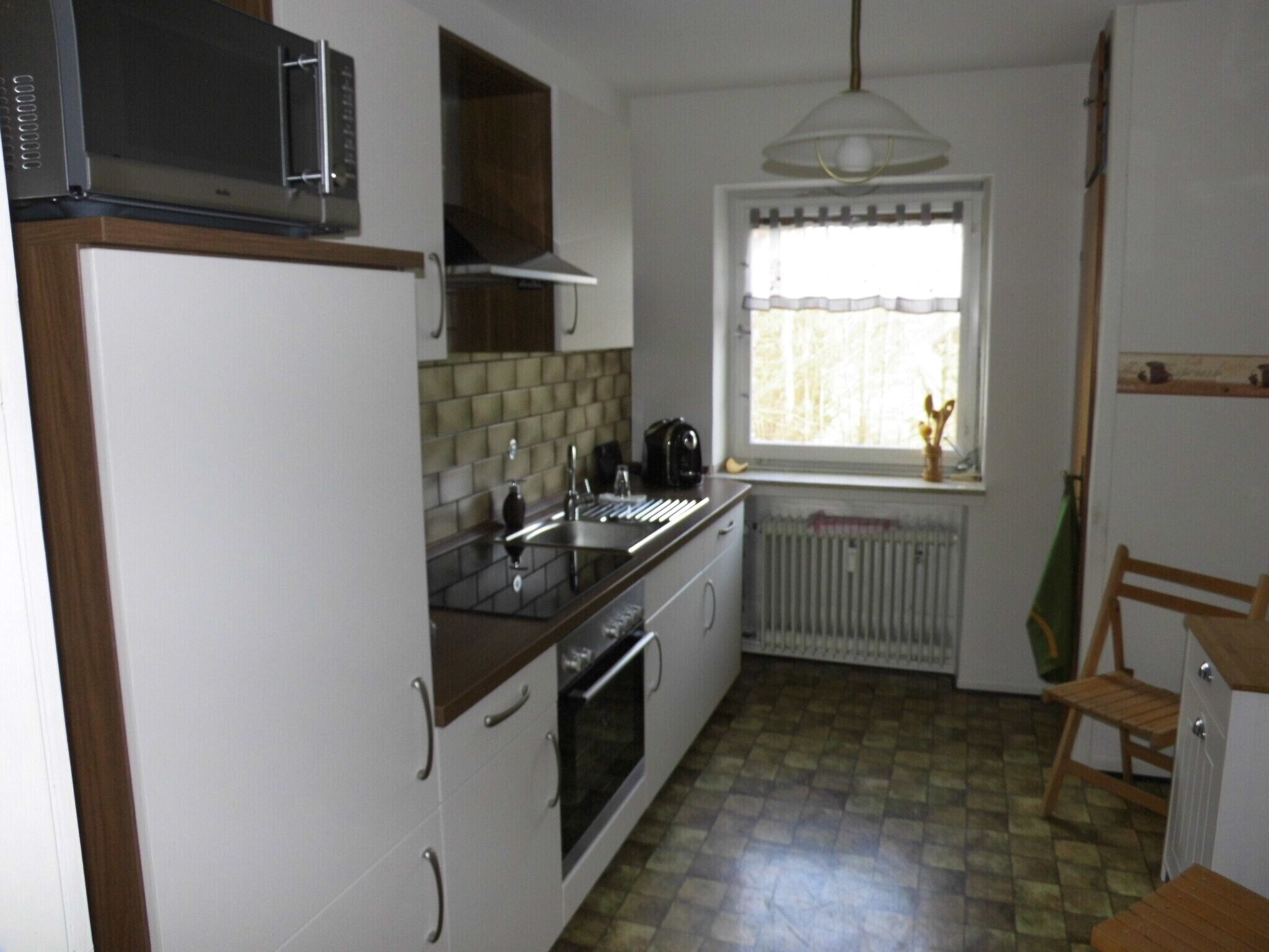 Eine Küche mit Mikrowelle, Backofen, Spüle und einem Fenster mit Vorhängen.