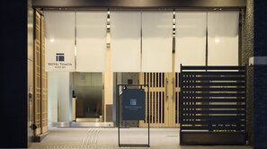 The entrance of Hotel Tomiya with a modern design, featuring a large glass door, a signboard, and a wooden gate. - HOTEL Tomiya with M's (Kyoto)