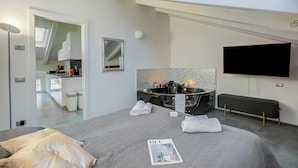 A modern hotel room with a large bed, a flat-screen TV, a hot tub, and a skylight. - Loft & Jacuzzi (Riva del Garda)