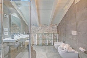 A modern bathroom with a glass shower enclosure, a white sink, and a bidet. - Loft & Jacuzzi (Riva del Garda)