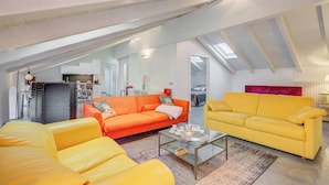 A loft-style living area with a high ceiling, a glass coffee table, and two sofas in bright colors. - Loft & Jacuzzi (Riva del Garda)