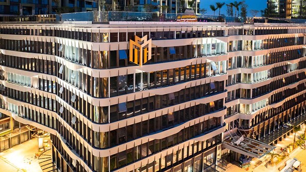 A multi-story hotel with a modern design, featuring a prominent logo on the facade. - The LUMIÈRE Riverside By An Gia Hospitality (Ho Chi Minh City)