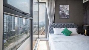 A modern hotel room with a large window offering a city view, a tufted headboard, and a framed abstract painting on the wall. - The LUMIÈRE Riverside By An Gia Hospitality (Ho Chi Minh City)