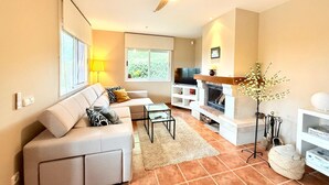 Un salon moderne comprenant un canapé, une table basse, un téléviseur, une cheminée et un ventilateur de plafond.
