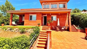 Une maison à deux étages dotée d’un patio, d’un porche couvert et d’un escalier menant à l’entrée.
