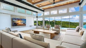 Un salón amplio con un televisor grande, asientos cómodos y vistas a un paisaje exuberante.